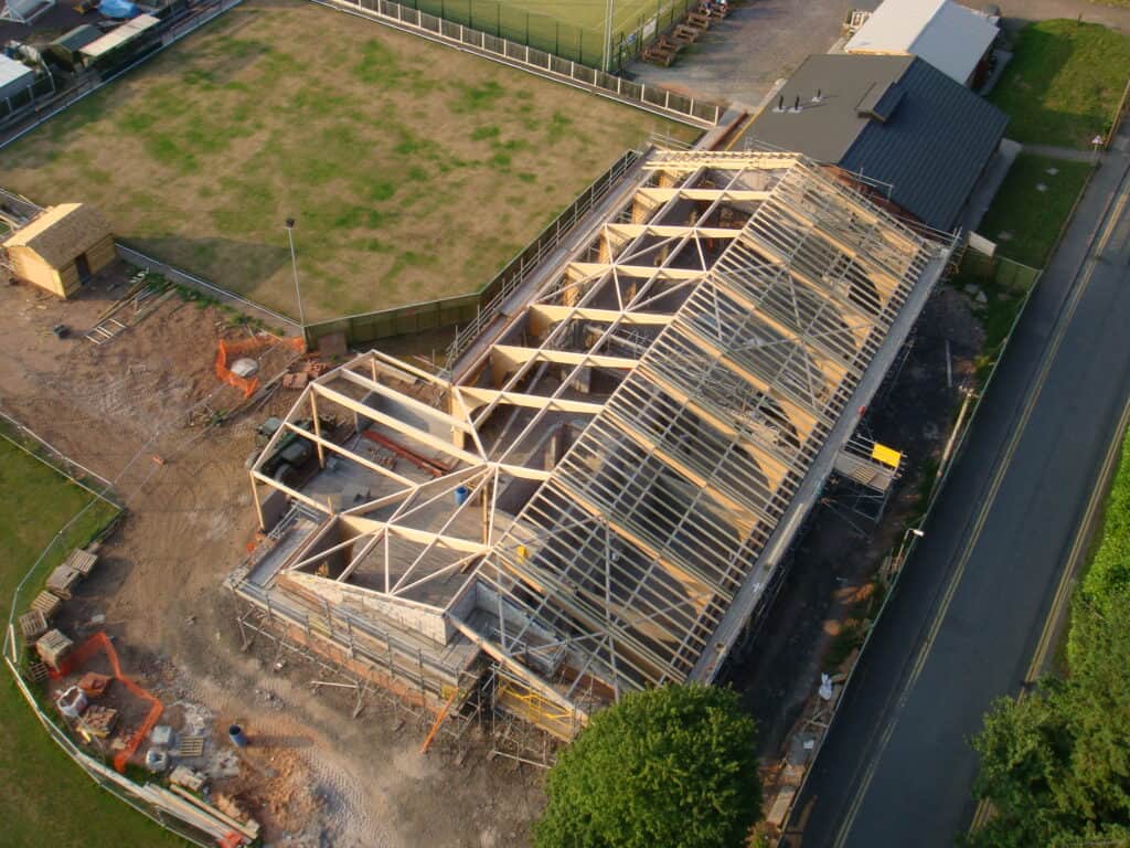 Aerial view of the historic Cookley Village Hall under construction, showcasing the wooden framework.