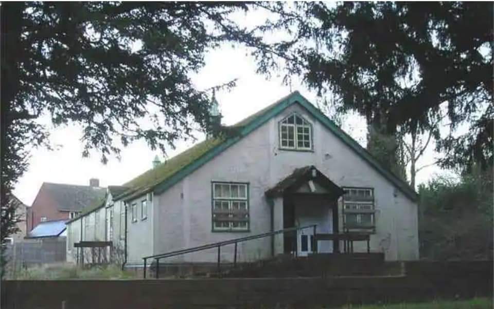 Historic village hall building with white walls and green roof in Cookley.